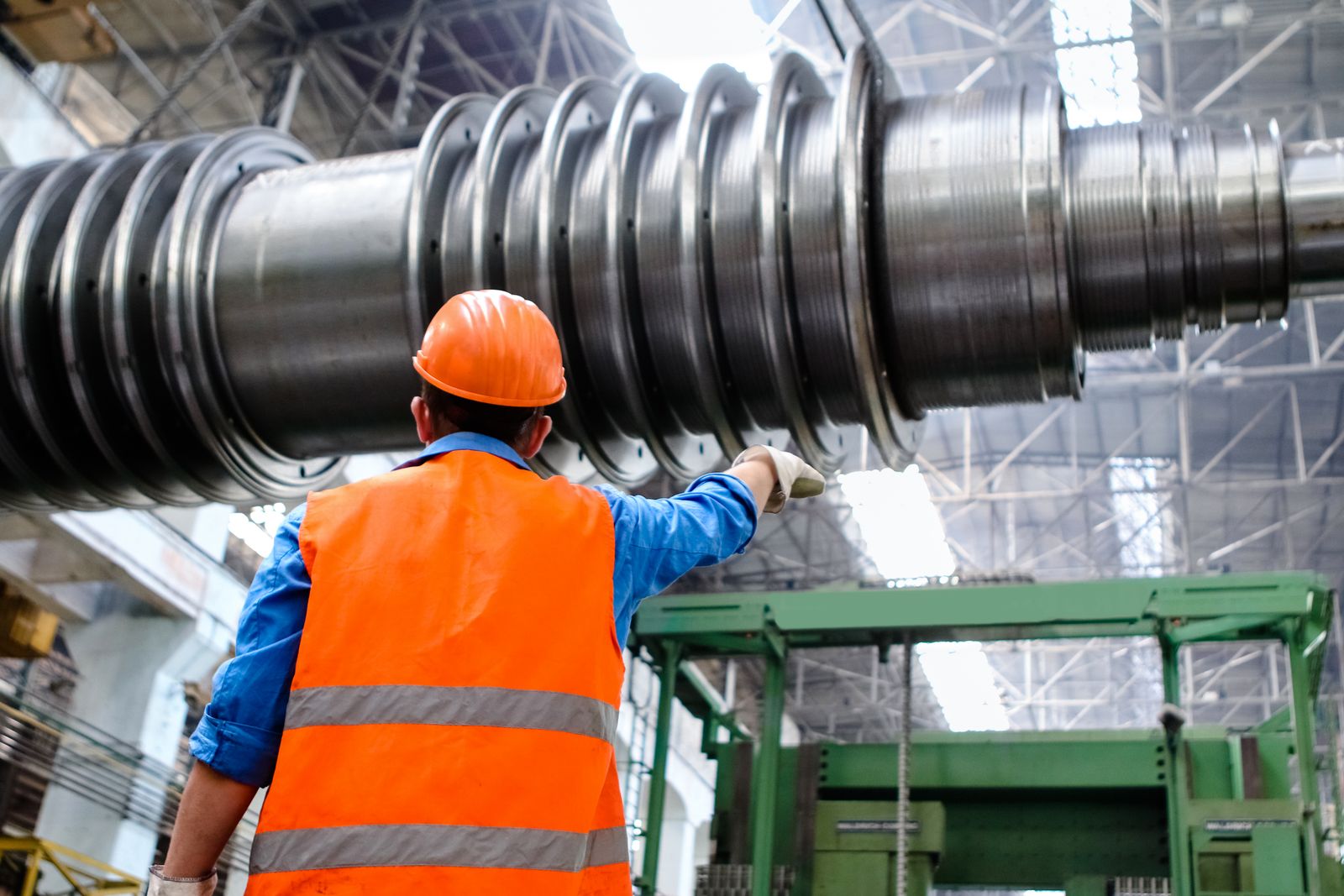 Engineer in high-visibility protective equipment inspecting industrial machinery